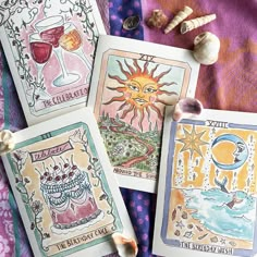 three cards with different designs on them sitting on a blanket next to garlic and cloves