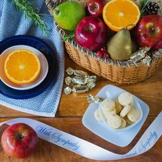 apples, oranges and pears in a basket next to a plate with silverware