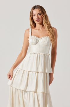 a woman wearing a white dress with ruffles on the bottom and spaghetti straps