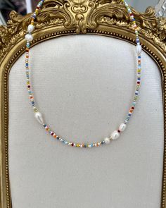 a gold frame with a beaded necklace hanging from it's side on display