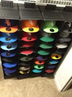 several bins filled with different colored hats on top of a carpeted floor next to a refrigerator