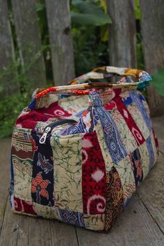 a multicolored patchwork bag sitting on top of a wooden table next to a fence