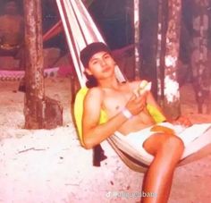 a woman sitting in a hammock holding a banana