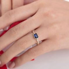 a woman's hand wearing a gold ring with an oval shaped blue sapphire stone