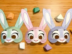 three paper bunny masks sitting on top of a wooden table next to dices and blocks