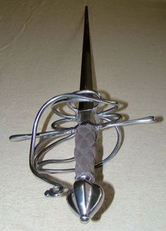 an odd looking metal object sitting on top of a white tablecloth covered floor with a knife sticking out of it's center