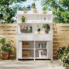 a white shelf filled with potted plants next to a wooden fence