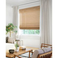 a living room with a couch, chair and window covered in bamboo blind shades on the windowsill