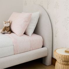 a teddy bear sitting on top of a bed next to pillows and blankets in a bedroom