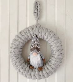 a knitted wreath with a gnome doll hanging on it