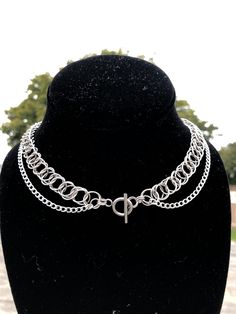 This is a shorter double stranded necklace that features a t bar closure in the middle of the necklace. The top strand is a chainmaille weave made with 10mm diameter jump rings. The entire necklace is made of 304 Stainless Steel. The top strand is about 15 inches.   Stainless steel is a great material for jewelry - it's tarnish and rust resistant, it's hypoallergenic (good for sensitive skin/ won't discolor your skin); it will last. To clean this piece just use some soap/water and a thorough dry, or dry it off after showering with it on. Adjustable Stainless Steel Chain Choker Necklace, Adjustable Stainless Steel Choker Chain Necklace, Adjustable Stainless Steel Chain Choker, Silver Toggle Choker Necklace With Lobster Clasp, Silver Toggle Clasp Chain Choker, Adjustable Sterling Silver Chain Choker, Silver Choker Chain Necklace With Toggle Clasp, Sterling Silver Chain Choker, Double Strand Silver Chain Jewelry