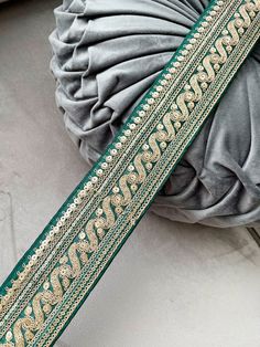 a green and gold sash laying on top of a white pillow next to a gray blanket