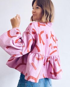 a woman wearing a pink top with red letters on it