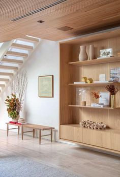 a living room filled with lots of furniture next to a stair case covered in vases