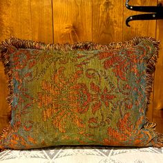 a green and orange pillow sitting on top of a bed next to a pair of scissors