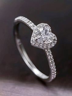 a heart shaped diamond ring on top of a table