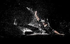 a man falling off his surfboard in the ocean at night time with water splashing all around him