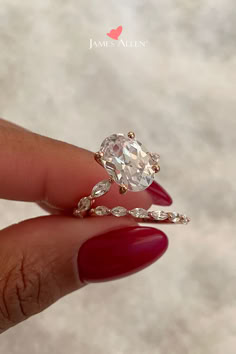 a woman's hand holding a ring with a large diamond in the middle and two smaller diamonds on each side