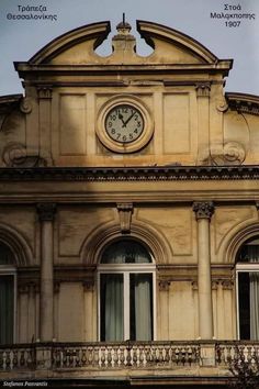 an old building with a clock on the top of it's face and balcony