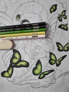 three pencils sitting next to each other on top of a sheet of paper with green butterflies