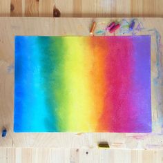 a rainbow colored painting is being made on a piece of wood