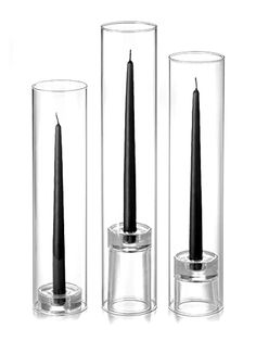 three glass vases with black candles in them