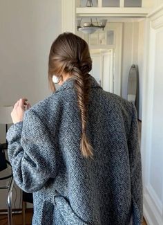 a woman standing in front of a door with her back to the camera, wearing a gray coat