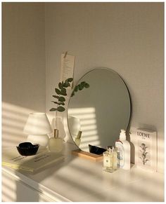 a white dresser topped with a mirror next to a lamp