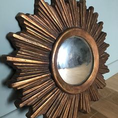 a gold sunburst shaped mirror on the wall