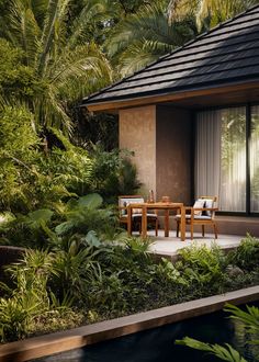 an outdoor dining area with table and chairs next to a pool surrounded by tropical vegetation