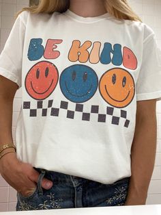 Look super cute and spread good vibes in this trendy retro Smiley Face Be Kind T Shirt!  Spread good vibes in this super soft comfort colors t shirt, and look great doing it! Please note: This item is PRINTED, not embroidered. Printed on a soft, 100% cotton comfort colors t shirt.  SIZING: Our T Shirts are unisex sizing.  We suggest ordering your normal size for a regular fit.  If you want an oversized fit we suggest ordering a size up. Please contact us directly for any custom/bulk orders! T Shirts Trendy, T Shirt Inspiration Design, Groovy T Shirt Designs, 90s Shirt Design, Trendy Multicolor T-shirt With Text Print, Trendy Relaxed Fit T-shirt With Cartoon Print, Trendy Cotton T-shirt With Retro Print, Casual Relaxed Fit T-shirt With Retro Print, Retro White T-shirt With Funny Print