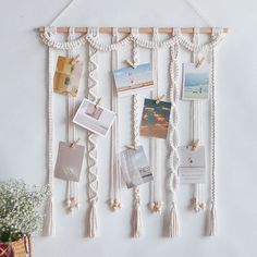 a white wall hanging with pictures, photos and other things attached to the strings on it