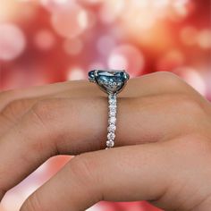 a woman's hand holding an engagement ring with blue and white diamonds on it