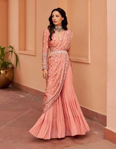 Introducing this enchanting peach sharara sari, crafted on a georgette base for a graceful drape. Paired with a printed hand-embroidered blouse and a chic belt, this ensemble embodies elegance with a contemporary twist. Make a statement at any event with this sophisticated fusion of style and tradition. Sharara Saree Style, Latest Sharara Designs Party Wear, Indian Sharara Outfits, Peach Indian Outfit, Pastel Indian Outfits, Indian Suit Ideas, Indian Fusion Outfits, Sharara Suit Designs Latest, Sharara Designs For Wedding