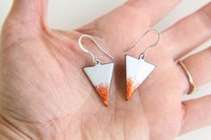 Vibrant pair of triangular earrings fired with multiple layers of white and orange enamel. These earrings have a real summer feel and would be great for carnival or the beach. Please note this item is made to order and therefore may differ slightly from the image shown due to the nature of enamel. These bright enamel triangle earrings measure approximately 23mm in length. They come with 925 Silver earring wires. The fiery coloured earrings would make the perfect gift for someone with a fire zodi White Triangle Earrings For Gift, Handmade White Enamel Earrings, Fire Zodiac Signs, Orange Enamel Dangle Jewelry, Summer Accessories Beach, Modern Triangle Metal Earrings, Nickel-free Orange Enamel Earrings, How To Polish Copper, Festival Earrings