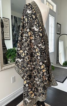 a mannequin wearing a black and gold kimono in front of a mirror