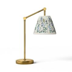 a lamp that is on top of a white surface with a gold base and shade