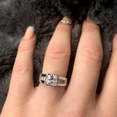 a woman's hand with a diamond ring on top of her finger and a fur background