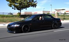 a black car driving down the road with a person in it's seat looking out the window