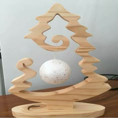 an ornament made out of wood with a white ball hanging from the top