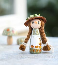 a doll is sitting on the table next to two mushrooms