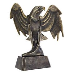 a bronze statue of an eagle with outstretched wings on a base, against a white background