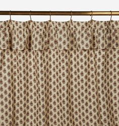 the curtain is hanging on a rod and has a flower pattern in brown, beige and white