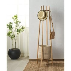 a hat and coat rack in front of a white wall with a potted plant