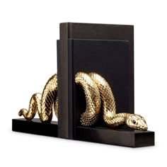 a golden snake sculpture sitting on top of a black bookender next to it's cover