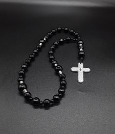 A very unique black Anglican Rosary that brings with it the power of the night prayer. The rosary is made of high quality Black Onyx gemstones, Miyuki Seed beads (which have been cleansed and purified) and a 304 Stainless Silver Cross with the Lord's Prayer engraved on it. Finally, the rosary has been blessed by the church. A rosary made to accompany you during your night prayers. Rosary: Anglican configuration Blessed: Yes About the Rosary: The Rosary has a Cross, an Invitatory bead, 4 sets of Spiritual Black Jewelry With Polished Beads, Black Onyx 8mm Beads, Black Spiritual Beads For Meditation, Black Beaded Cross-shaped Rosary, Black Beaded Cross Rosary, Black Obsidian 8mm Bead Jewelry, Black Cross Jewelry With 8mm Beads, Black Hematite Spiritual Jewelry, Black Spiritual Cross Jewelry