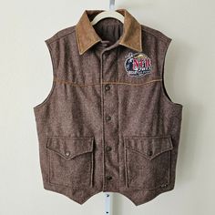 Wrangler Men's 2013 Las Vegas Nfr Limited Edition Pro Rodeo Gear Wool & Leather Blend Insulated Zipper Button Vest Sz M -Brown Colored Wool And Leather Blend Insulated Limited Edition Pro Rodeo Gear Nfr Vest With A Front Zipper And Button Closure -Foldable Light Brown Leather Neck Collar With Two Front Snap Button Flap Pockets And One Inside Pocket Located On The Left Mid Inside Portion Of The Vest With Attached Replacement Button -Intricate Embroidery Of "Wrangler Nfr 2013 Prca Prorodeo Las Veg Western Brown Outerwear With Button Closure, Men’s Western Vest Outfit, Western Rodeo Vest, Snap Button-up Tops For Rodeo, Vintage Brown Vest With Button Closure, Light Brown Leather, Neck Collar, Flap Pocket, Front Zipper