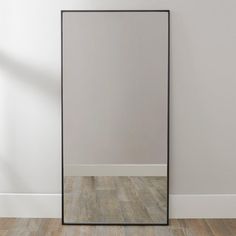 a large mirror sitting on top of a wooden floor in front of a white wall