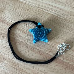 a blue star on a black cord with a silver metal charm hanging from it's end