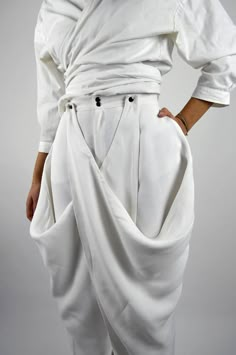 Made in FranceProduct description :- Very wide white pants,- High waist,- Invisible pockets and back darts,- Panels on the sides that attach to the belt or that can be left hanging,- Closed with a zip fly and a metal snap button.The Balmorra Pant is caracterized and formed delicately bu light, free and fluid curves. The pant recalls the inspirations of travel to which the Louise Marcaud brand attaches itself by adding its own touch of minimalism with fine and clean lines. Bold, lightweight trous Wide White Pants, Illustration Fashion Design, Clothing Details, Fashion Hacks Clothes, Pants Design, Fashion Design Clothes, Pants Pattern, White Pants, Fashion Details